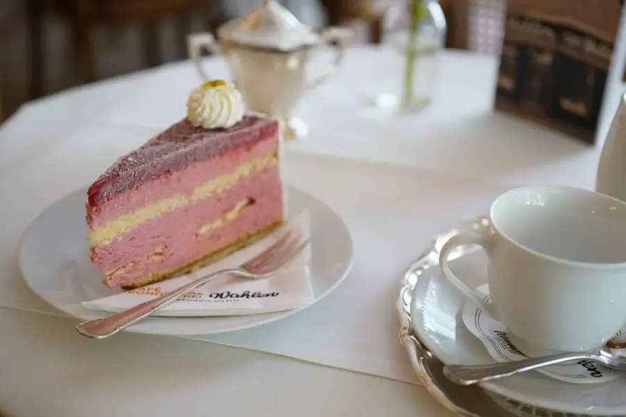 Stück Eistorte mit rosa Fruchtschicht und Kaffeegedeck