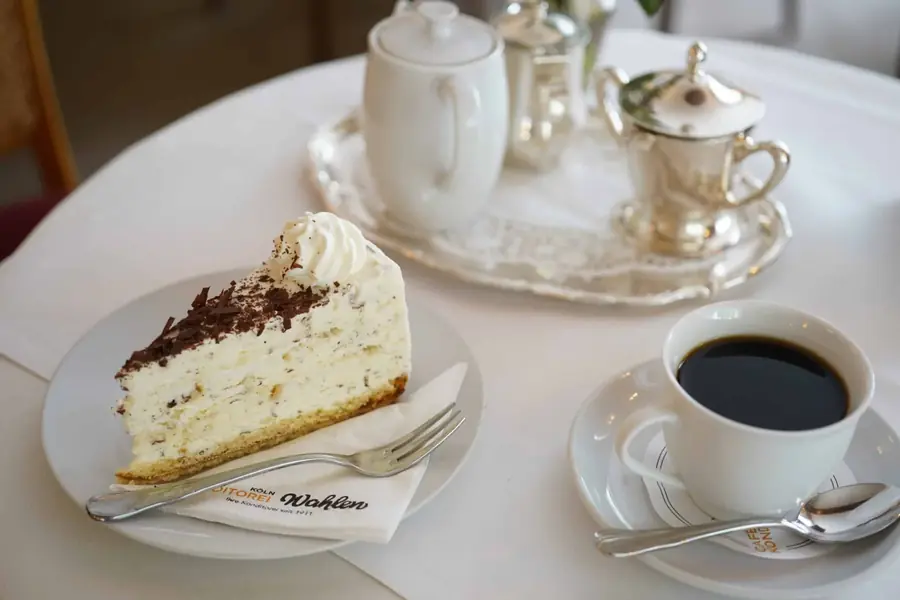 Stück Eistorte mit Sahne und Schokoladensplittern neben einer Tasse Kaffee