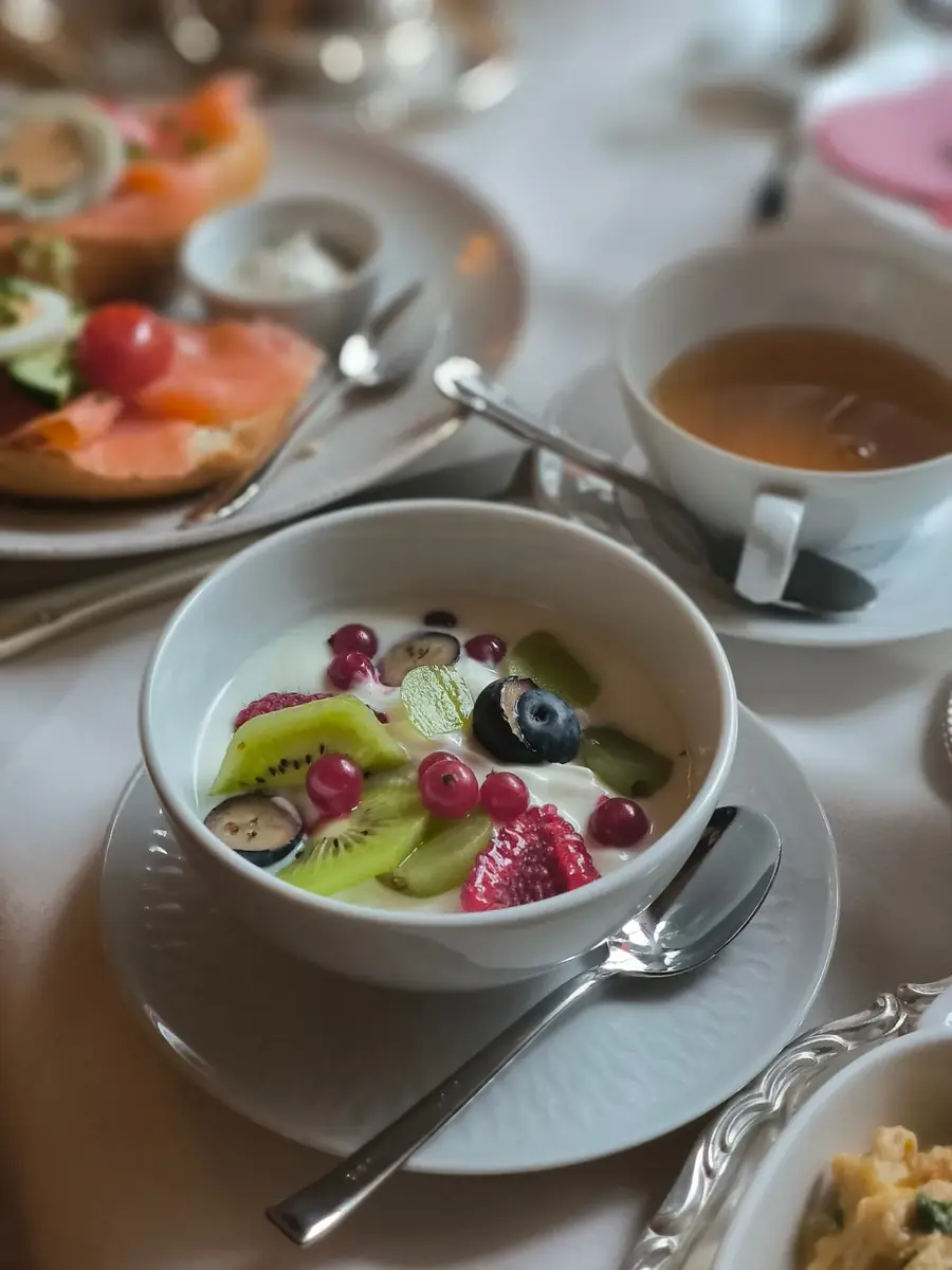 Naturjoghurt mit frischen Früchten neben Lachsbrot und Kaffee