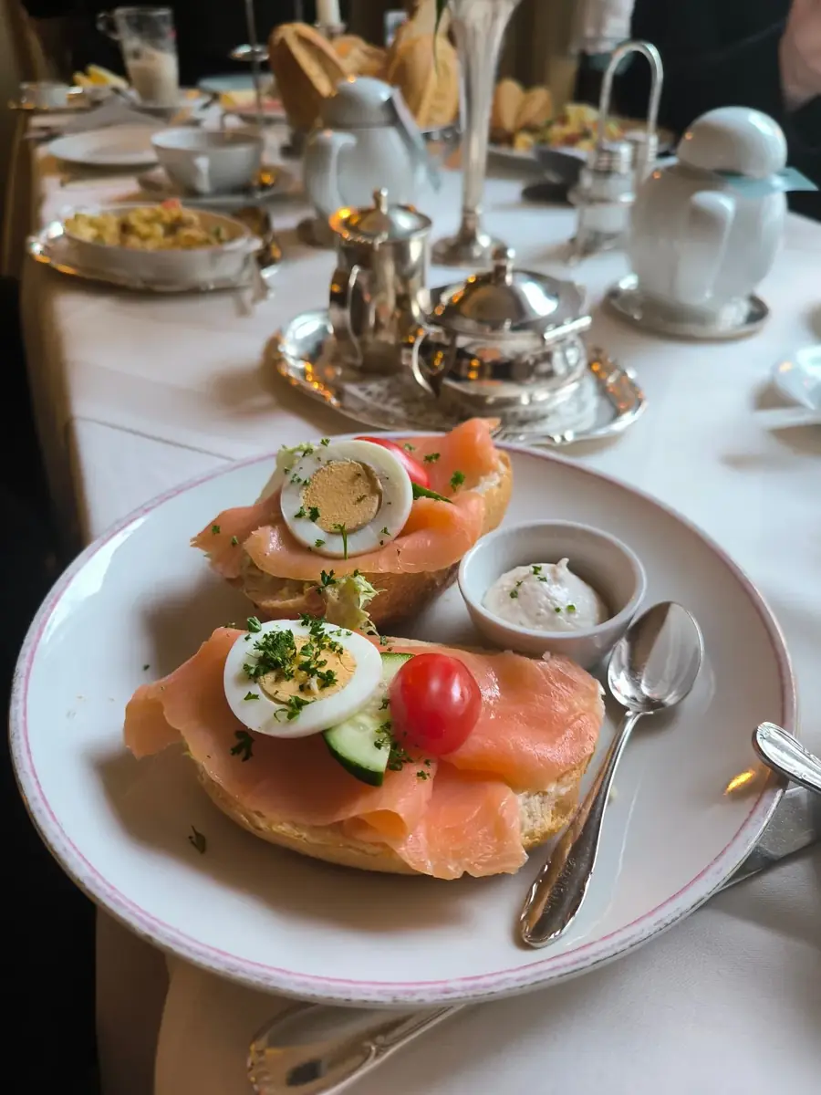 Frühstücksteller mit Lachsbrot, Rührei und silbernem Teeservice
