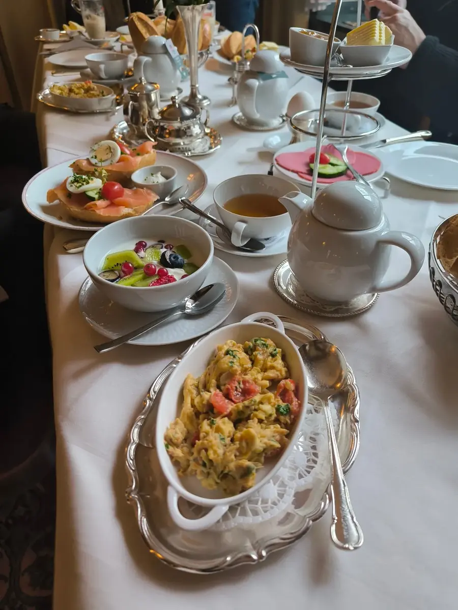 Reich gedeckter Frühstückstisch mit Etagere, Rührei und Kaffeegedeck