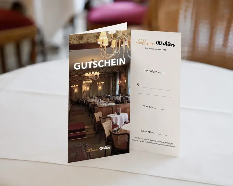 Aufgestellter Gutschein der Café Konditorei Wahlen auf einem eingedeckten Tisch