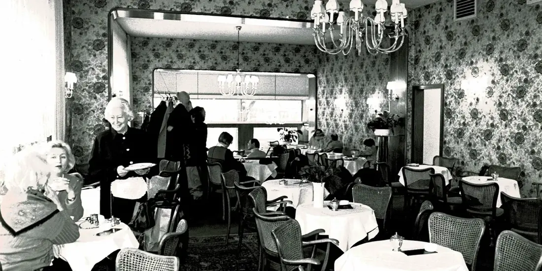 Gäste an gedeckten Tischen unter Kronleuchtern im Café Wahlen