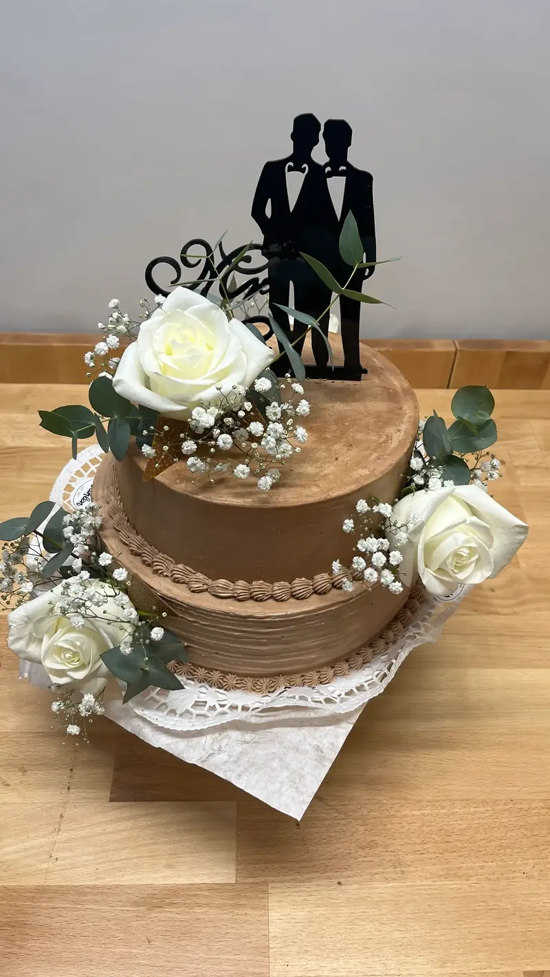 Zweistöckige Hochzeitstorte mit Figuren-Aufsatz und weißen Rosen