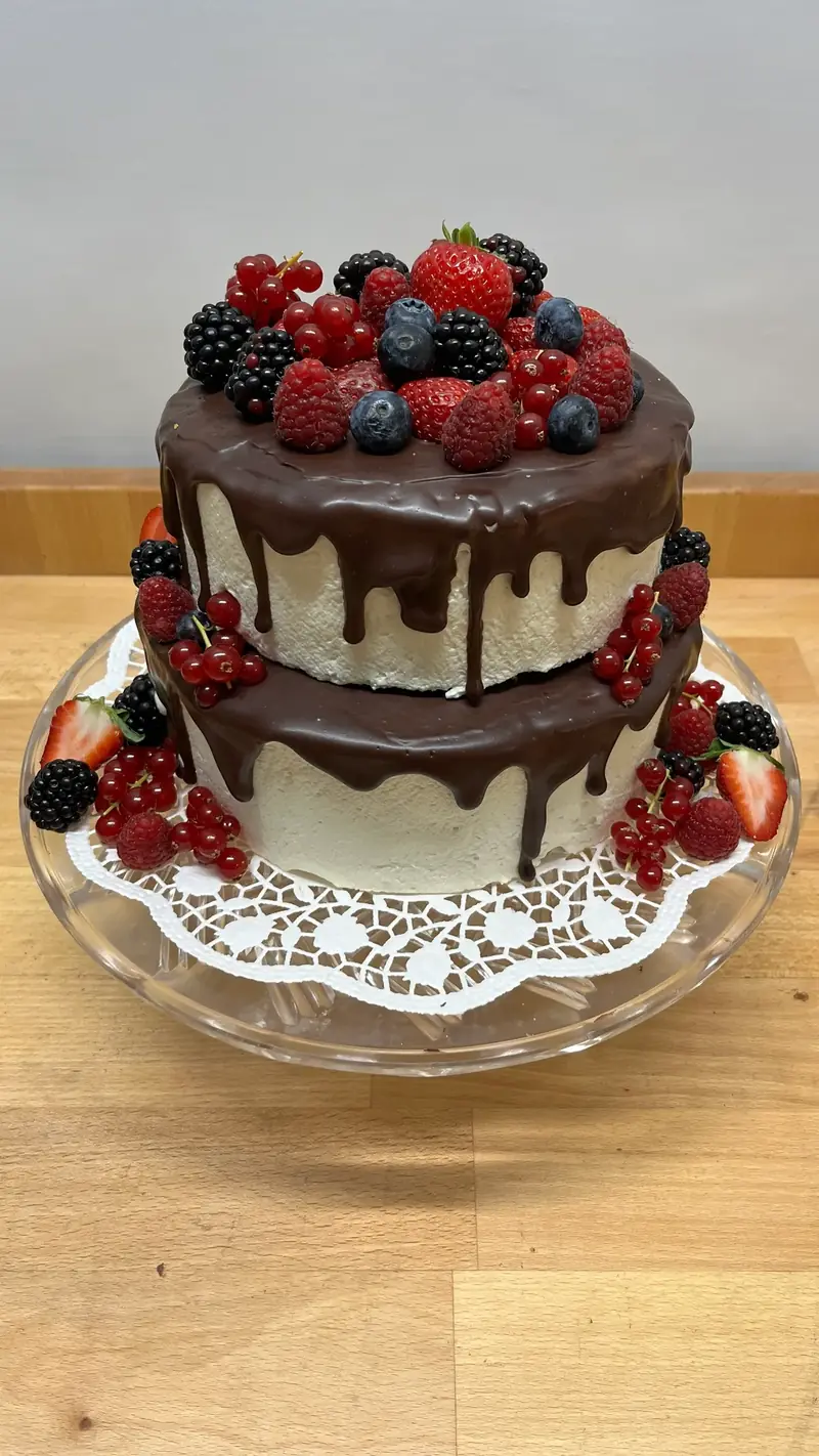 Zweistöckige Torte mit Schokoladenguss, frischen Beeren und Feigen
