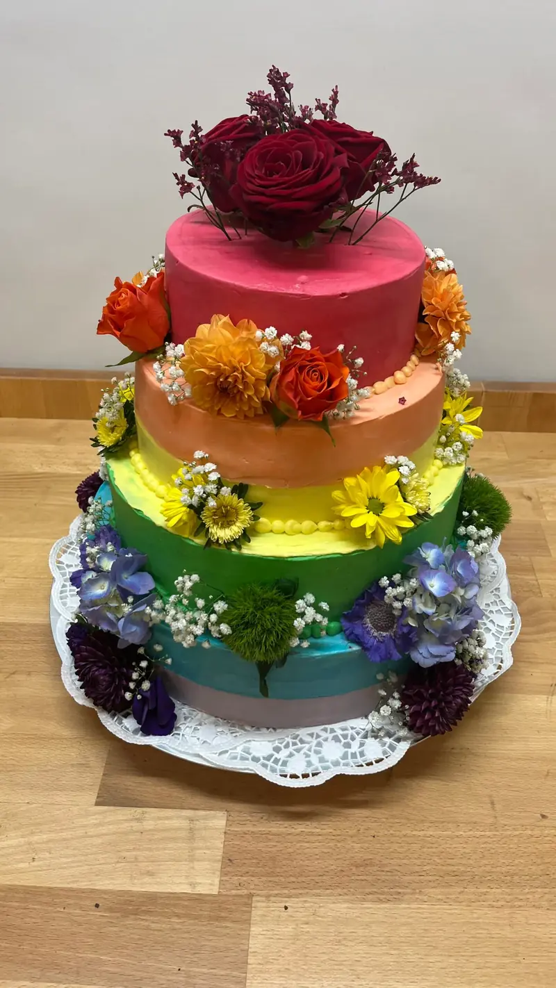 Dreistöckige Torte in kräftigen Farben mit Blüten und Früchten