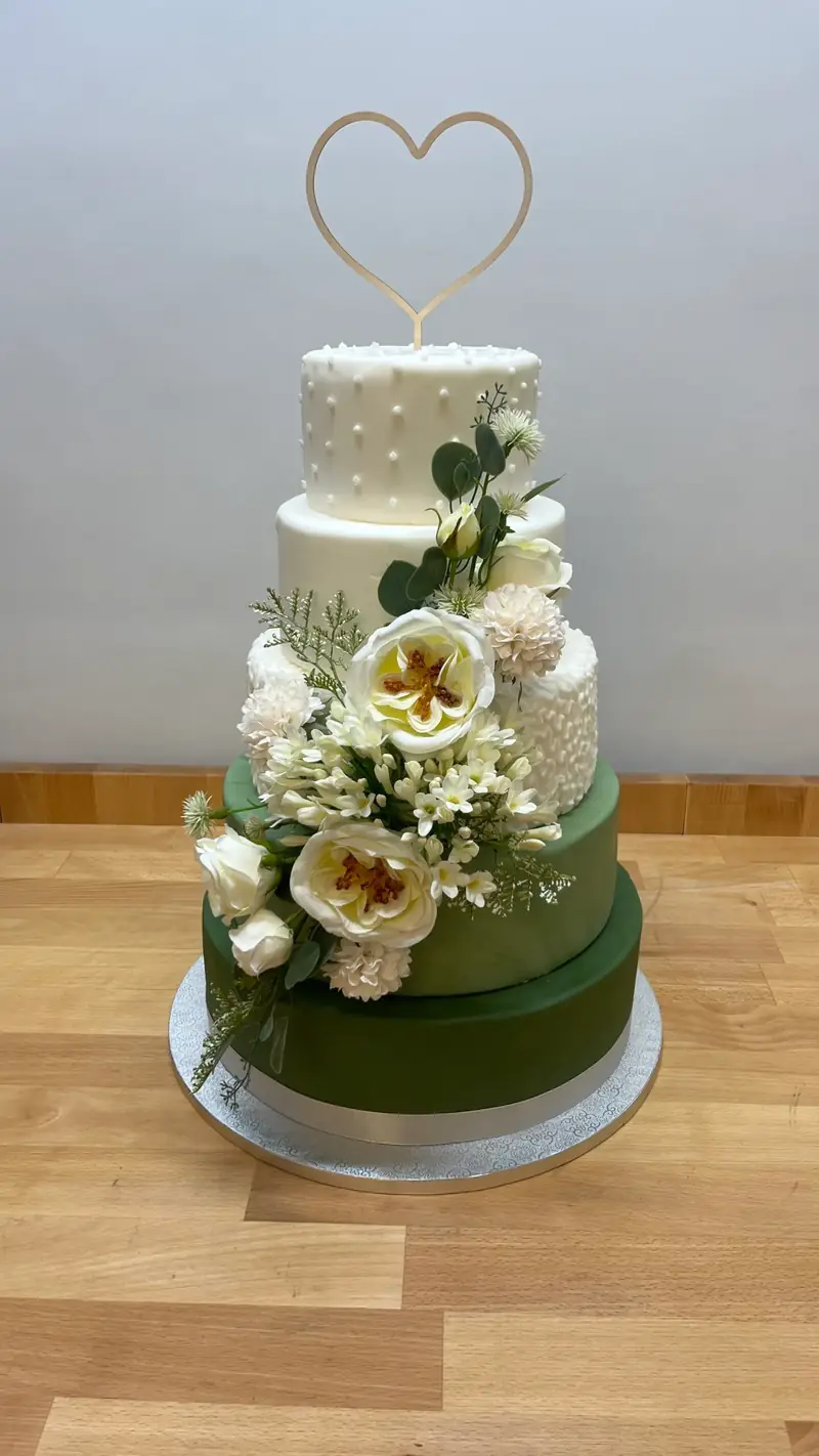 Dreistöckige Torte in Weiß und Dunkelgrün mit Blüten und Herz-Aufsatz