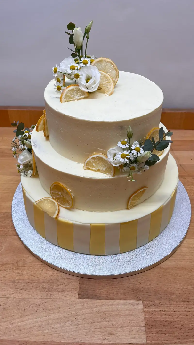 Dreistöckige Torte in Weiß und Gold mit Blüten und Figuren-Aufsatz
