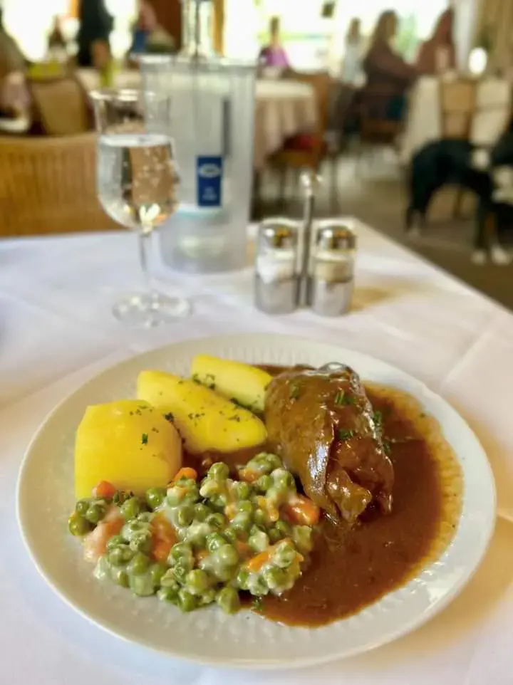 Braten mit Salzkartoffeln und Erbsen-Möhren-Gemüse im Café