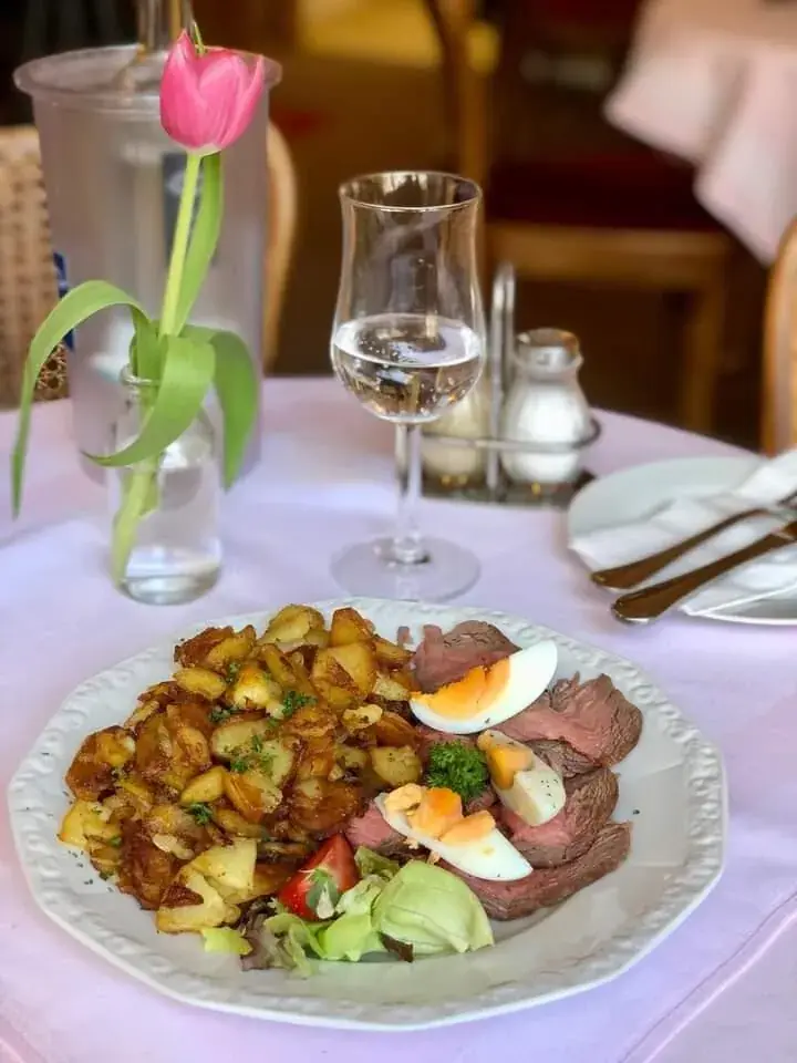 Roastbeef mit Bratkartoffeln, Ei und Avocado auf gedecktem Tisch
