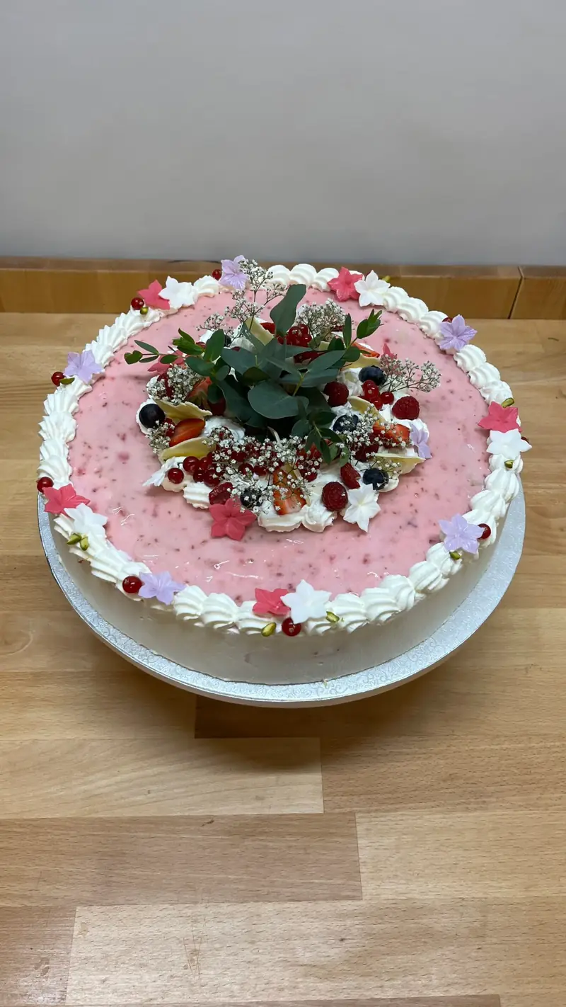 Torte in Rosa mit Sahnetupfen, Blüten und frischen Beeren