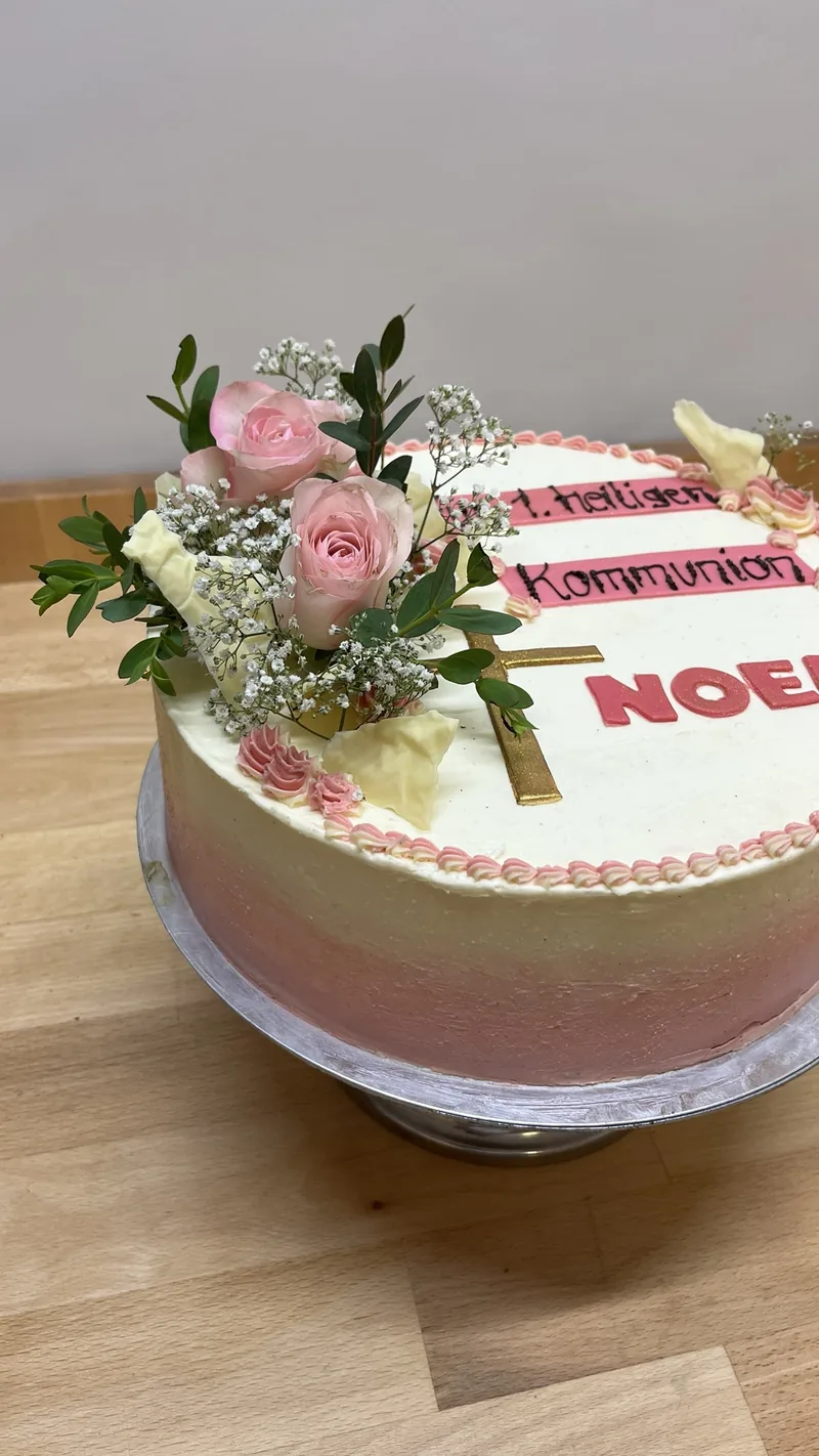 Torte mit rosé Farbverlauf, frischen Rosen, Schleierkraut und goldenem Kreuz zur Kommunion