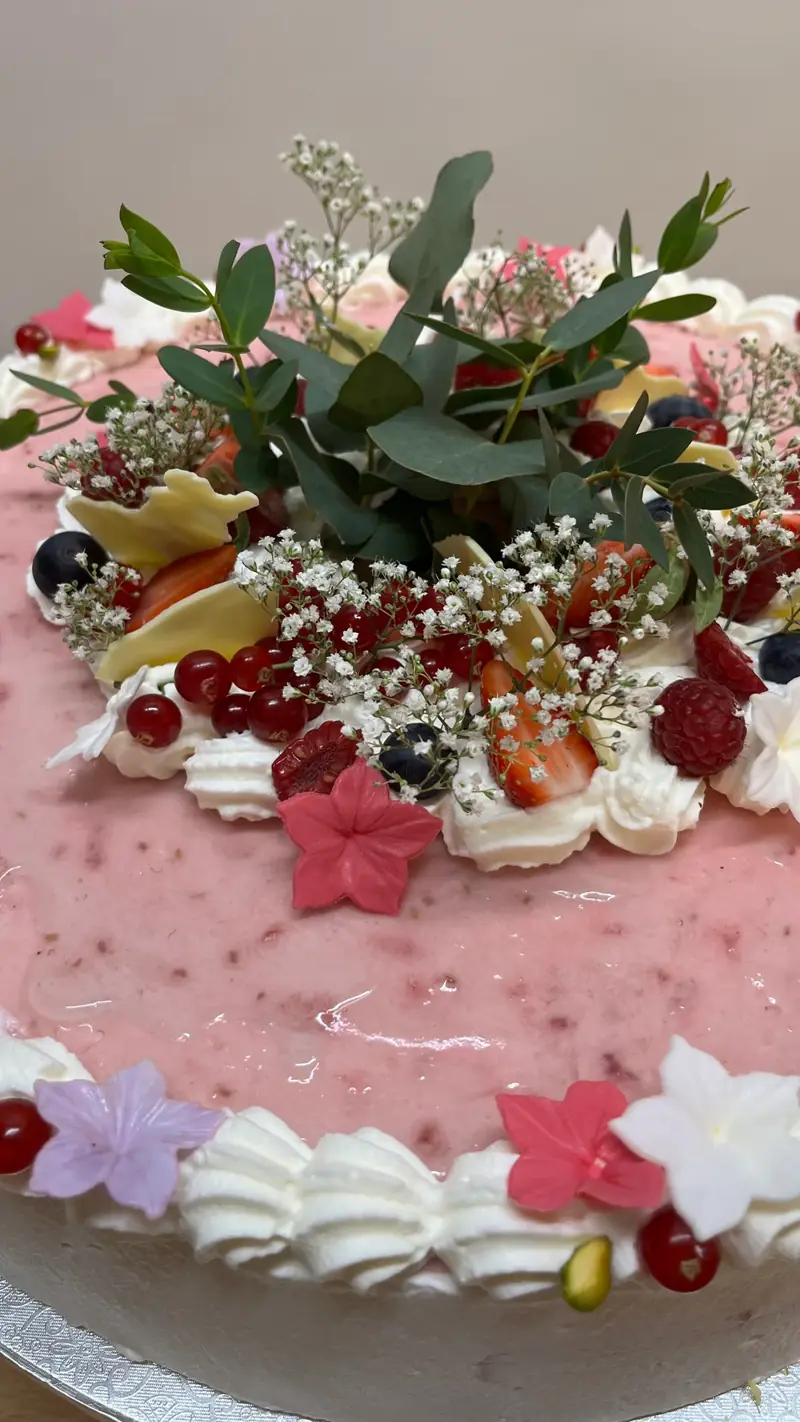 Torte mit Baiser, Beeren und frischen Blüten